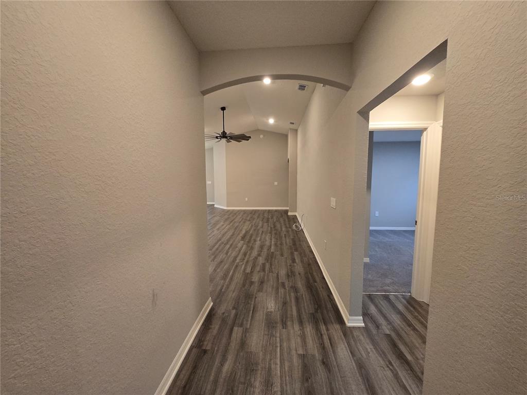 A hallway with wood-look flooring leads to an open living area with a ceiling fan — 1352 MOUNTAIN FLOWER LANE, DAVENPORT, FL