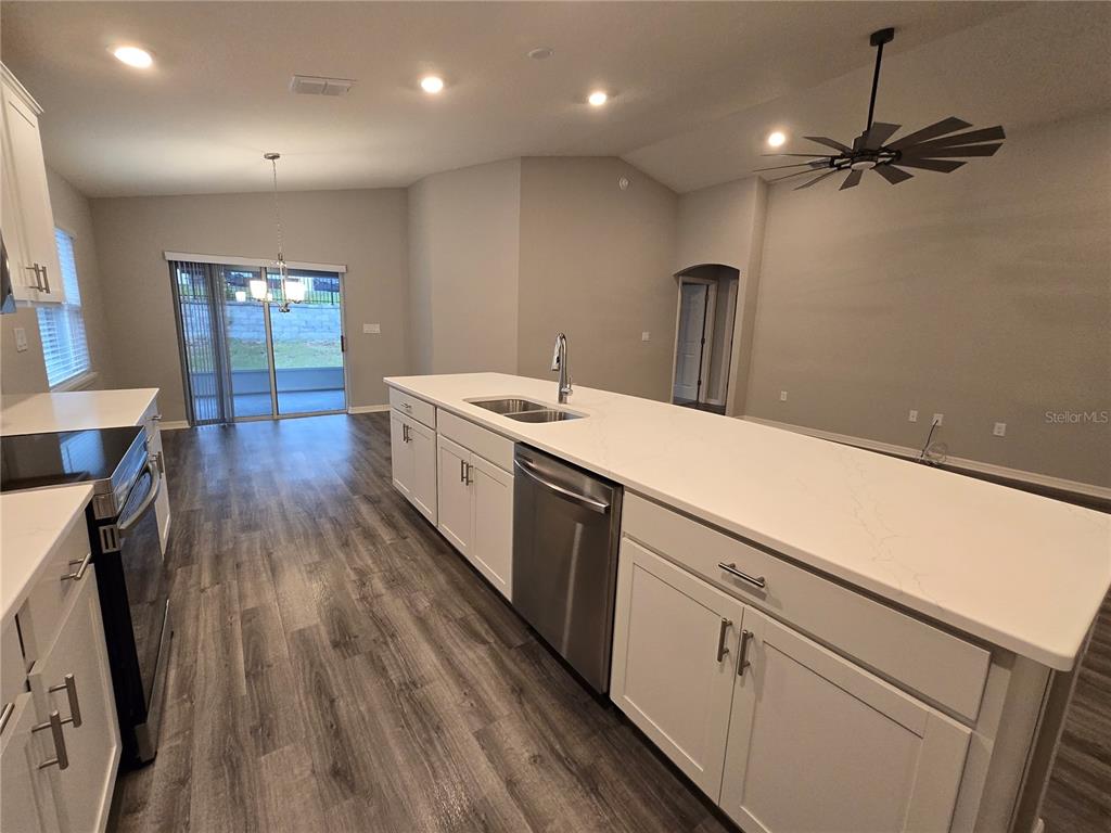 A kitchen features white cabinets, a large island with a sink, and wood-look flooring — 1352 MOUNTAIN FLOWER LANE, DAVENPORT, FL