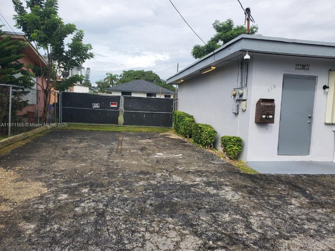 A paved parking area sits in front of a gray building with a gray door — 512 SW 6th Ave, Homestead FL 33030, HOMESTEAD, FL