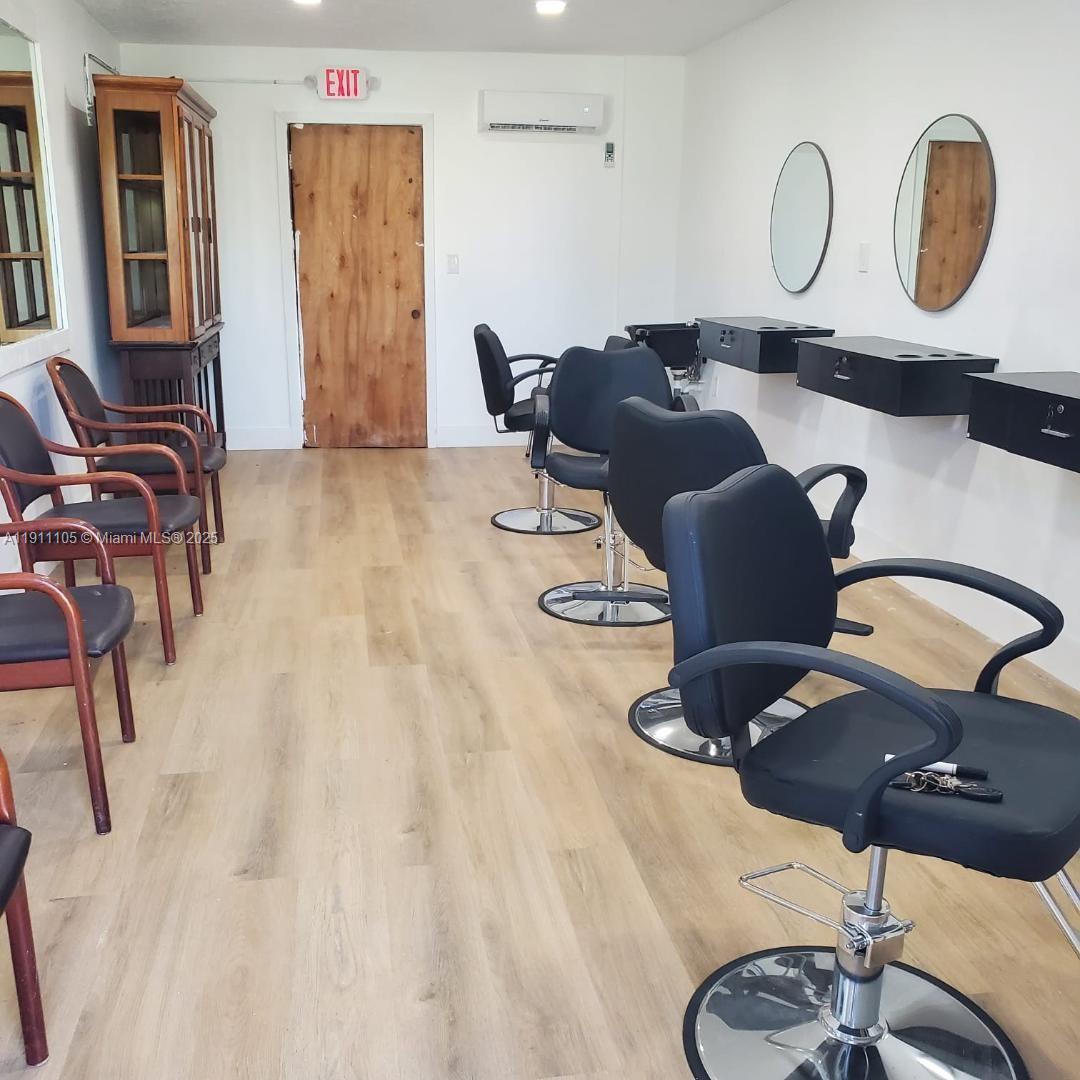 A hair salon interior features black styling chairs, wall-mounted stations, mirrors, and wood-look flooring — 512 SW 6th Ave, Homestead FL 33030, HOMESTEAD, FL