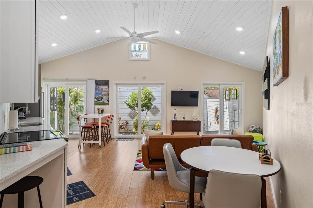 An open-concept living and dining area features vaulted ceilings, wood-look flooring, and sliding glass doors — 1500 9TH AVENUE N, ST PETERSBURG, FL