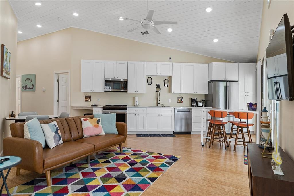A kitchen and living area with white cabinets, a brown sofa, and a colorful rug — 1500 9TH AVENUE N, ST PETERSBURG, FL