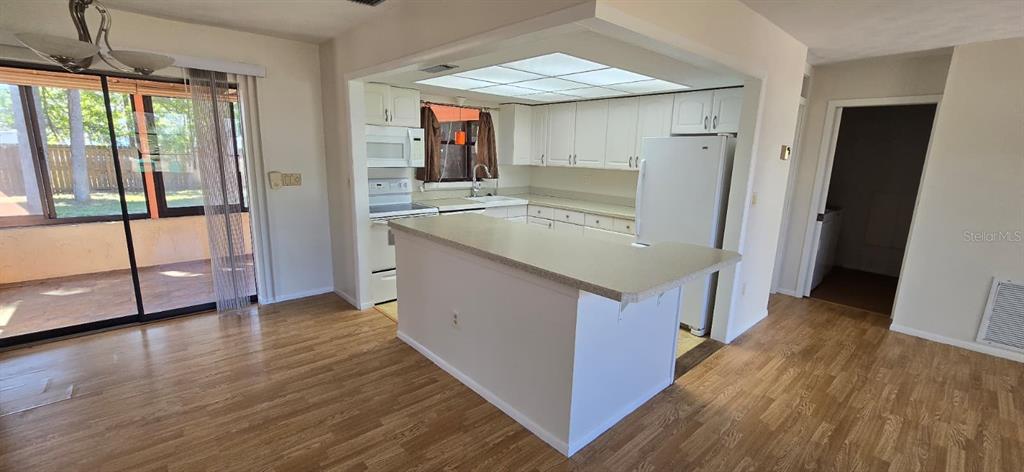 A kitchen with white cabinets, a breakfast bar, and light wood-look flooring — 2395 ALDA LANE, PORT CHARLOTTE, FL
