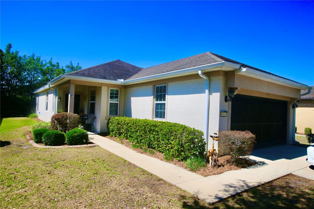 A single-story house with a tan stucco exterior, a dark roof, and a two-car garage — 9134 SW 73RD STREET, OCALA, FL