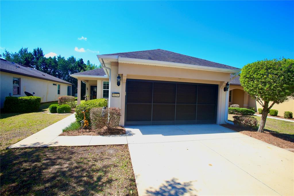 A single-story house with a beige stucco exterior, a dark garage door, and a driveway — 9134 SW 73RD STREET, OCALA, FL