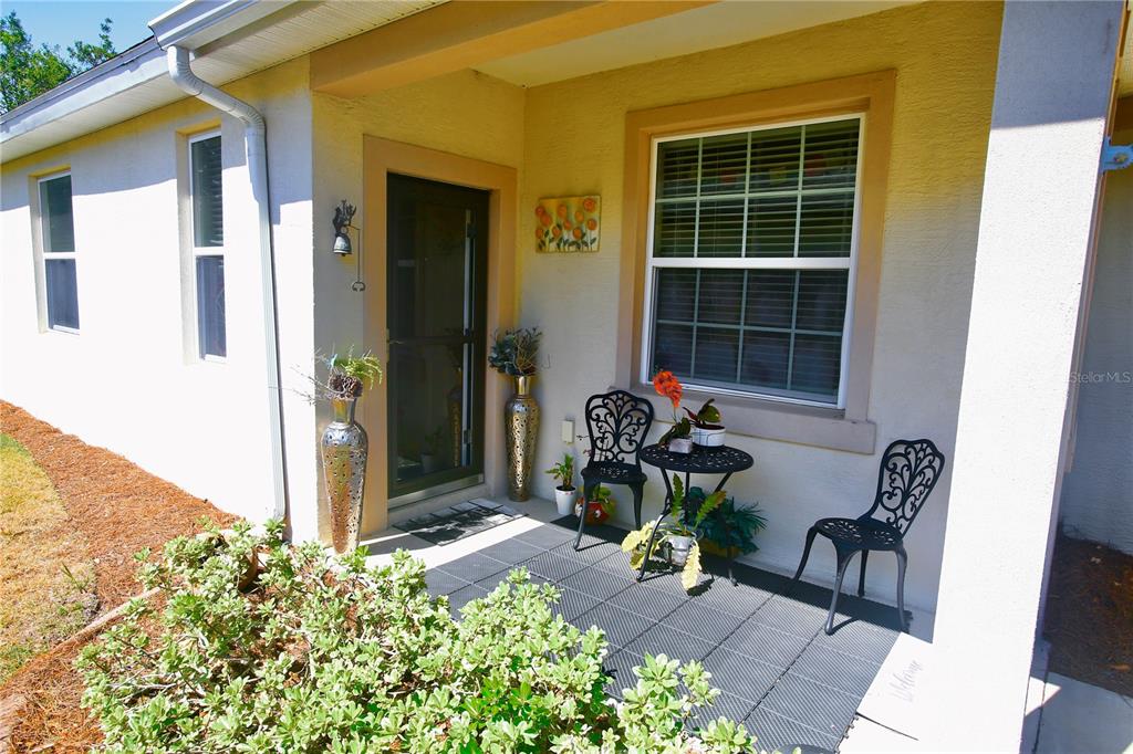 A covered front porch features a screen door, a window, and patio furniture — 9134 SW 73RD STREET, OCALA, FL