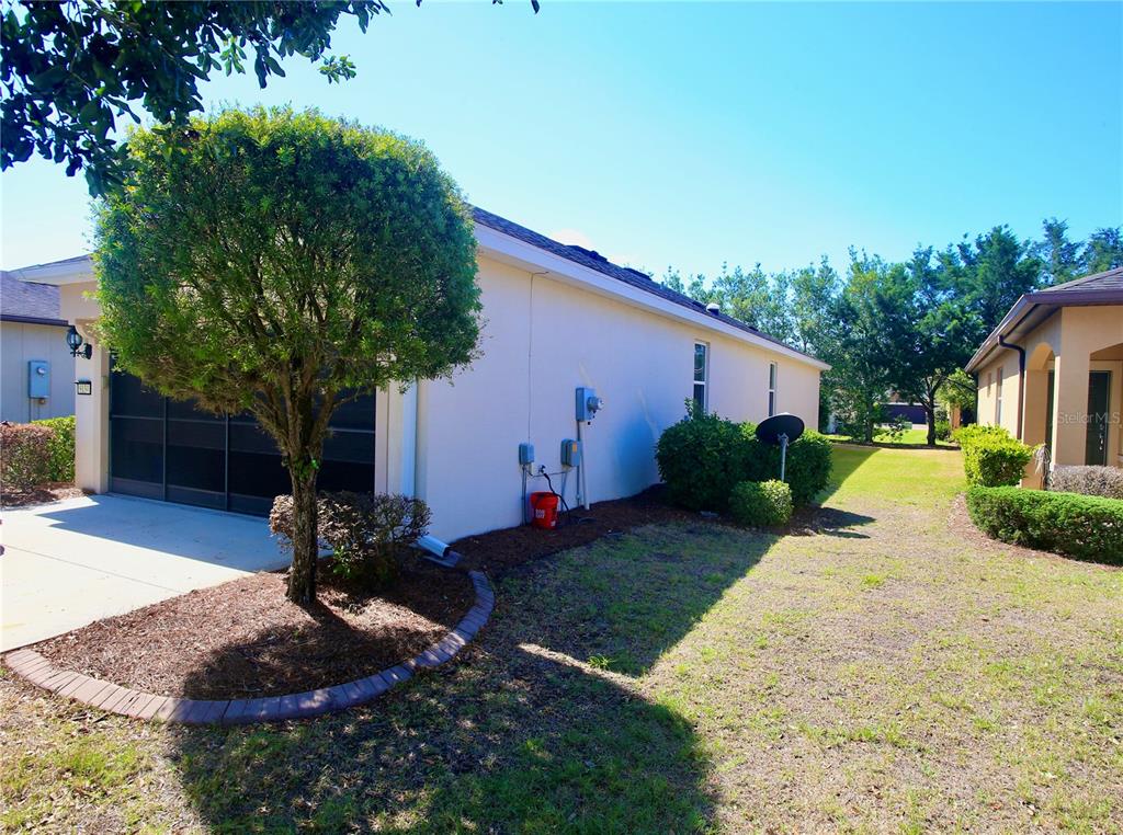 A side view of a house exterior featuring a garage, landscaping, and a grassy yard — 9134 SW 73RD STREET, OCALA, FL