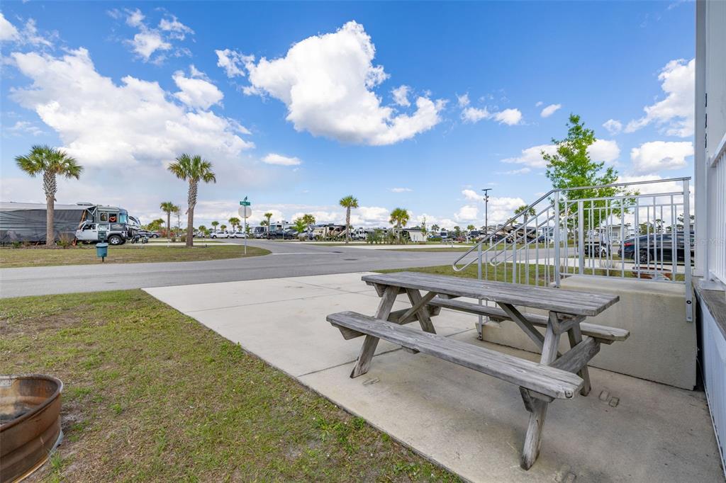 A wooden picnic table sits on a concrete patio next to metal stairs outdoors — 325 TIKI TURN (HWY 630) E, LAKE WALES, FL