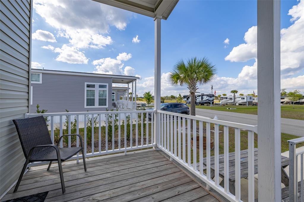 A wooden porch with a chair and white railing overlooks a neighborhood of manufactured homes — 325 TIKI TURN (HWY 630) E, LAKE WALES, FL