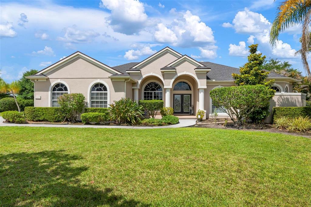 A single-story house with a beige stucco exterior, arched windows, and a manicured front lawn — 22610 NIGHT HERON WAY, BRADENTON, FL