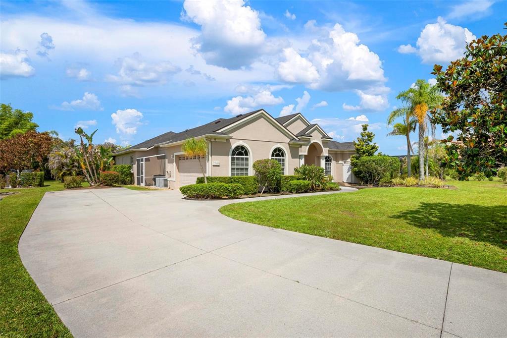 A single-story house with a beige exterior, a concrete driveway, and a manicured lawn — 22610 NIGHT HERON WAY, BRADENTON, FL