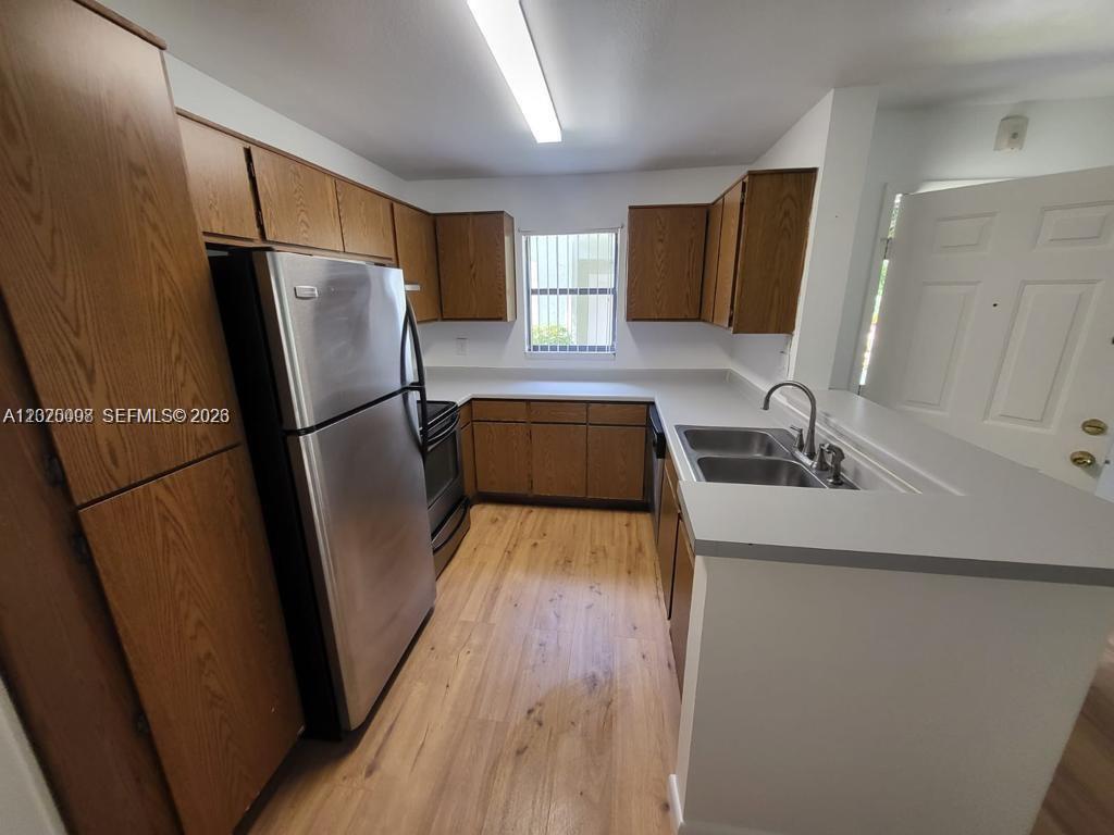 A kitchen features wood cabinets, stainless steel appliances, light countertops, and wood-look flooring — 4028 NW 87th Ave # 4028, Sunrise FL 33351, SUNRISE, FL