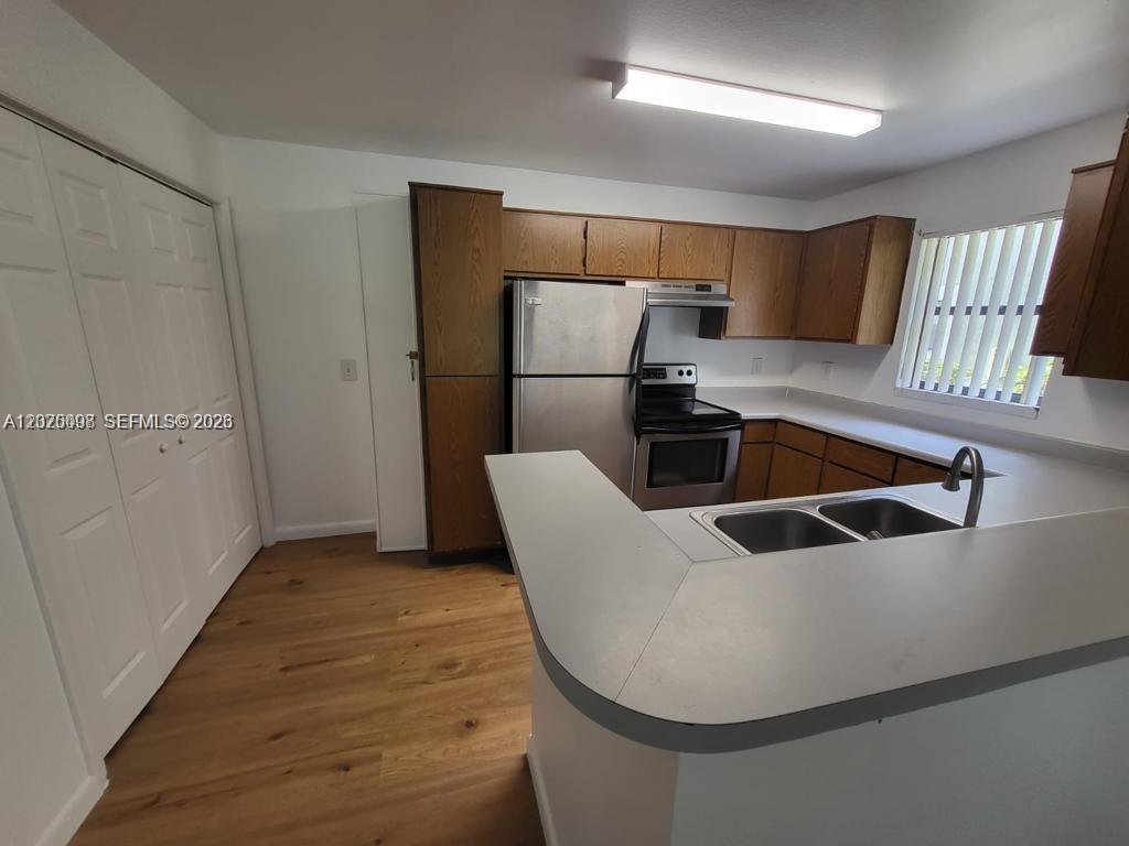 A kitchen features wood cabinets, stainless steel appliances, a peninsula counter, and light wood flooring — 4028 NW 87th Ave # 4028, Sunrise FL 33351, SUNRISE, FL