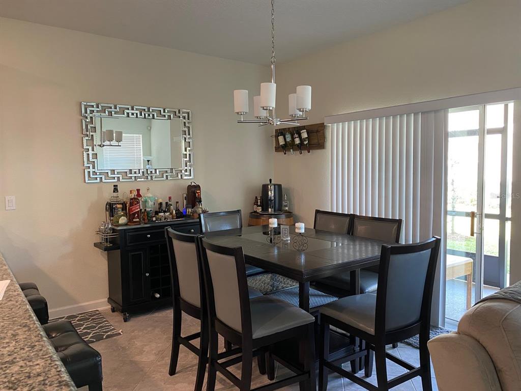 A dining room features a dark wood table, matching chairs, a bar cabinet, and a mirror — 15222 HARRINGTON COVE DRIVE, ORLANDO, FL