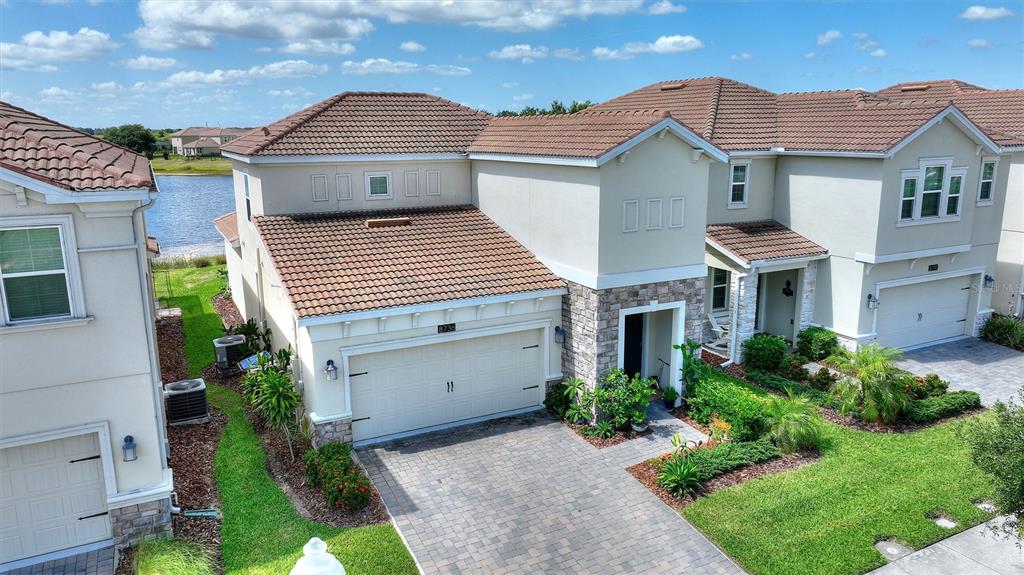 An exterior view of a two-story suburban house with a tiled roof and stone accents — 8736 PACIFIC DUNES DR, DAVENPORT, FL