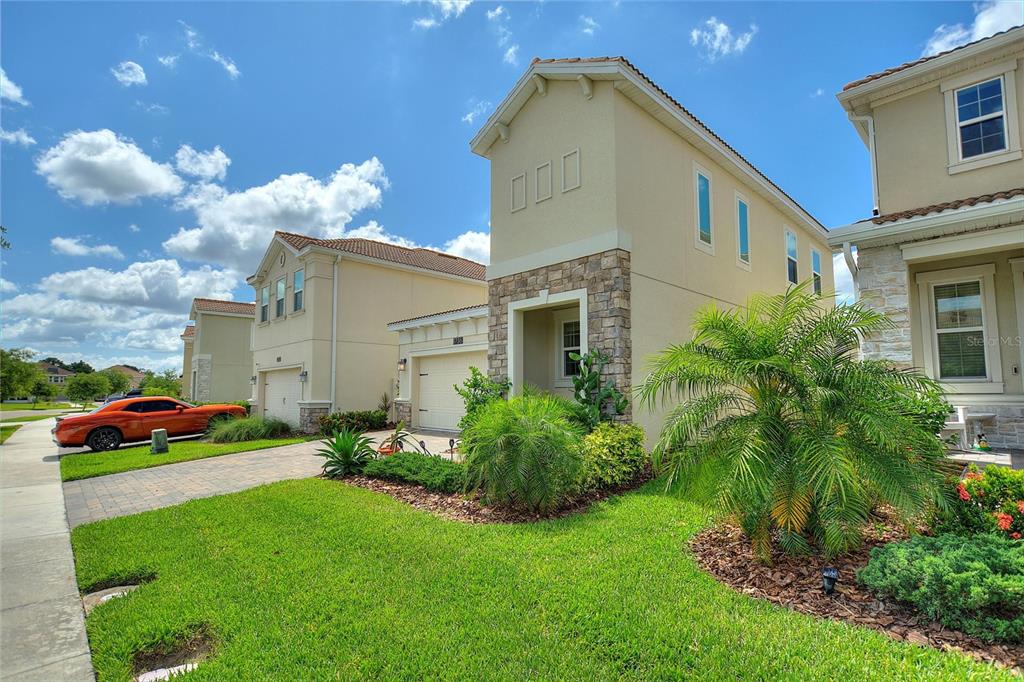 A view of the exterior of a two-story suburban home with a stone-accented entryway — 8736 PACIFIC DUNES DR, DAVENPORT, FL