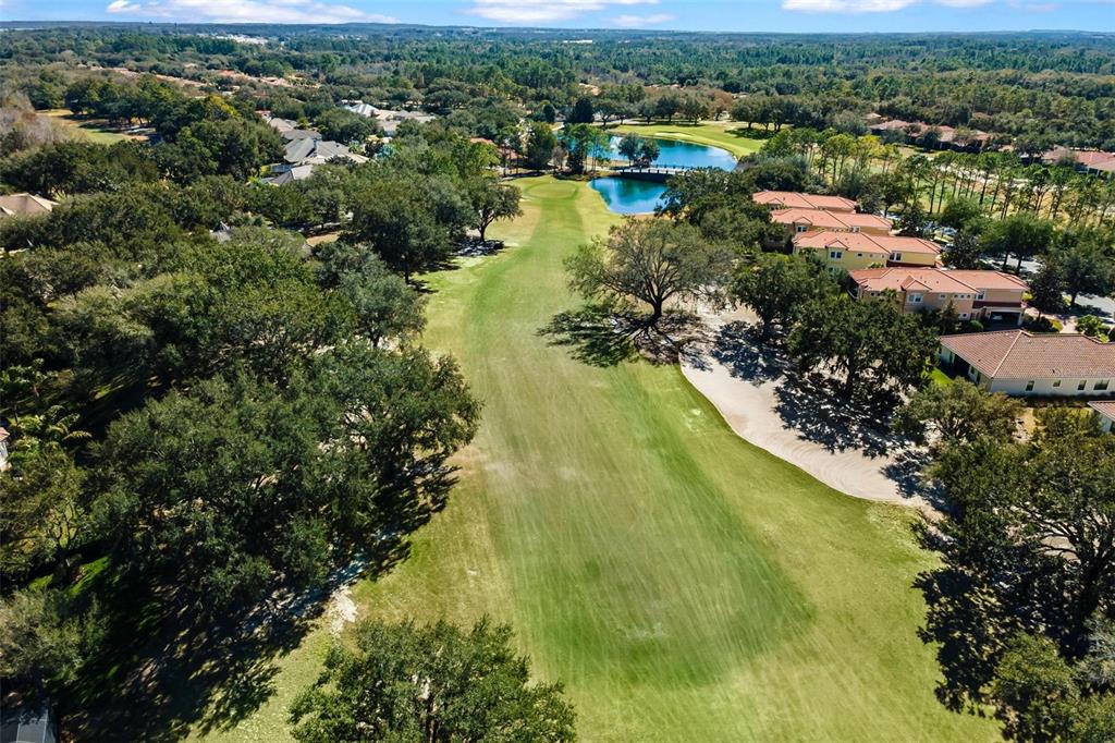 An aerial view shows a golf course fairway lined with trees and residential buildings — 26309 SAN GABRIEL, HOWEY IN THE HILLS, FL