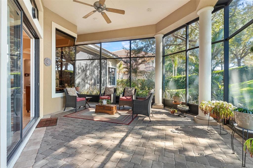 A screened-in patio features stone pavers, white columns, a ceiling fan, and outdoor furniture — 26309 SAN GABRIEL, HOWEY IN THE HILLS, FL