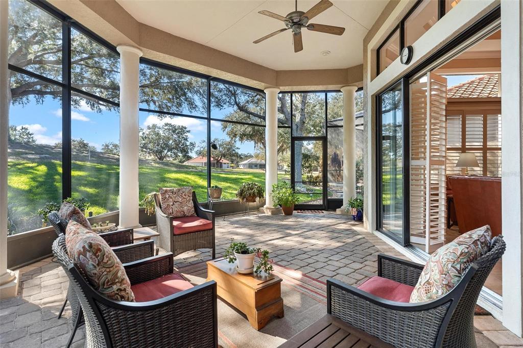 A screened-in patio features a paver floor, white columns, and a view of a grassy yard — 26309 SAN GABRIEL, HOWEY IN THE HILLS, FL