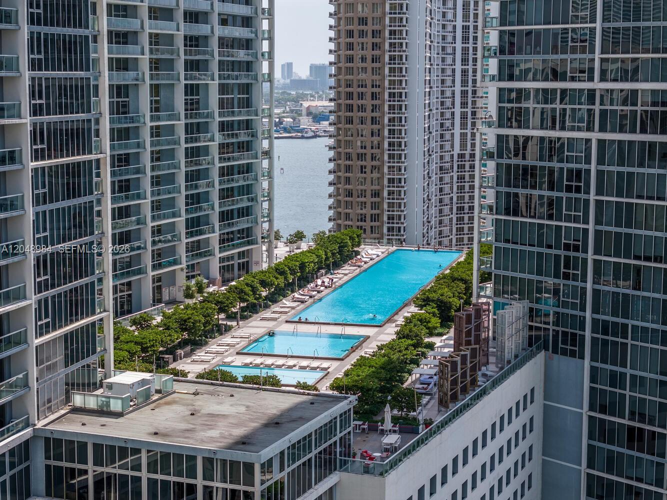 An elevated view shows a long swimming pool nestled between several tall glass apartment buildings — 465 Brickell Ave # 3506, Miami FL 33131, MIAMI, FL