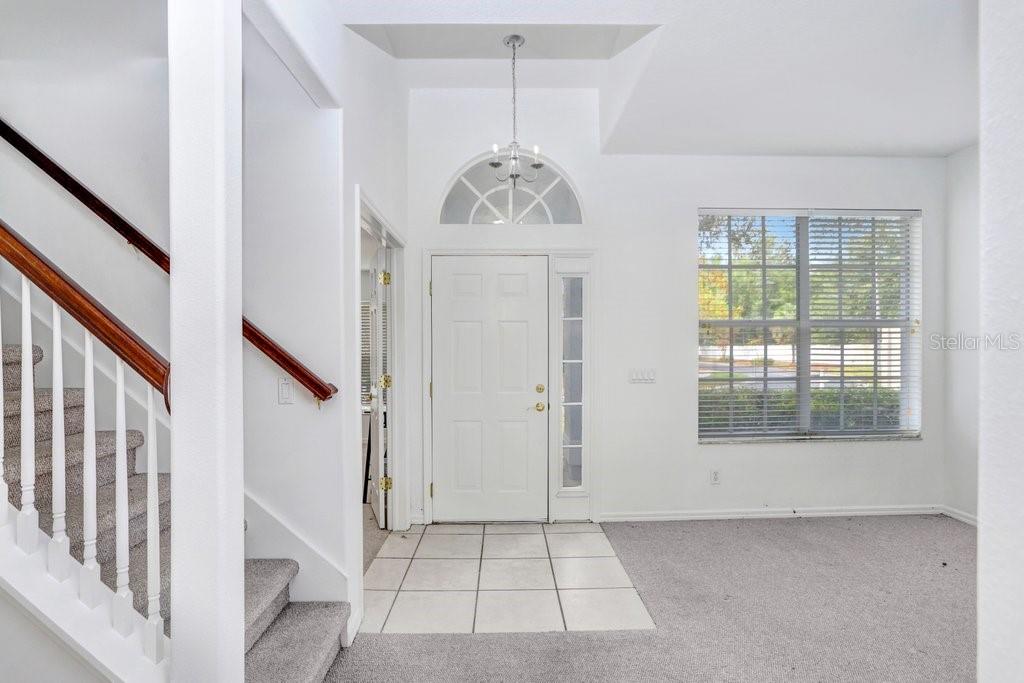 An entryway features a white front door, a staircase with carpeted steps, and tile flooring — 2927 MINUTEMAN LANE, BRANDON, FL