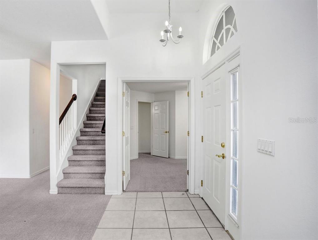 An entryway features a tiled floor, a carpeted staircase, and a white front door — 2927 MINUTEMAN LANE, BRANDON, FL