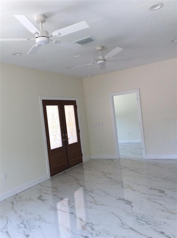 A room with white walls, marble-patterned tile flooring, two ceiling fans, and double entry doors — 2812 DURHAM STREET, TAMPA, FL