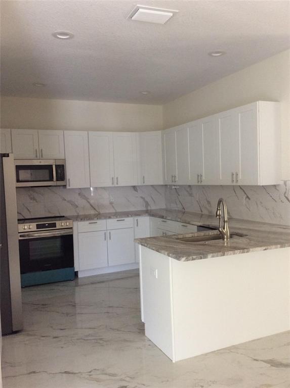 A kitchen with white cabinets, marble-patterned countertops, and matching marble-look flooring — 2812 DURHAM STREET, TAMPA, FL