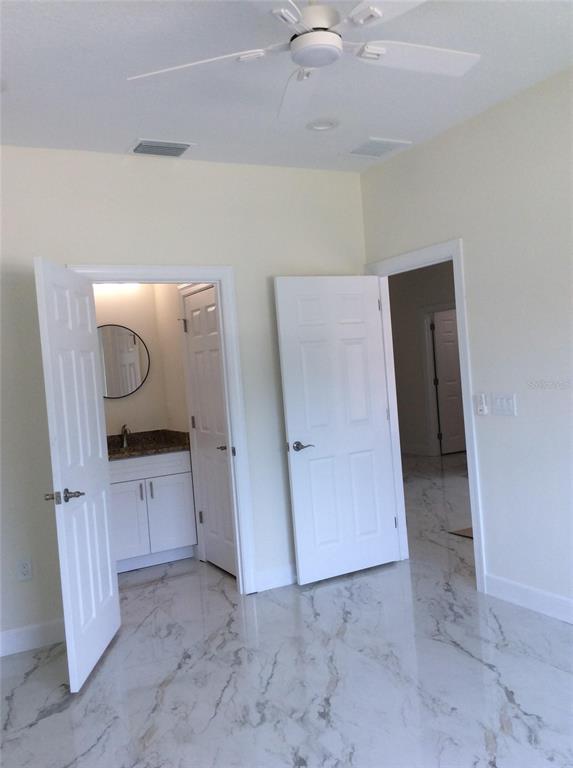 An interior view shows two open white doors, a bathroom vanity, and marble-patterned tile flooring — 2812 DURHAM STREET, TAMPA, FL
