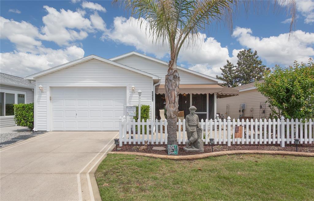 A white single-story house features a garage, a front porch, and a white picket fence — 2427 SOUTHERN OAK STREET, THE VILLAGES, FL