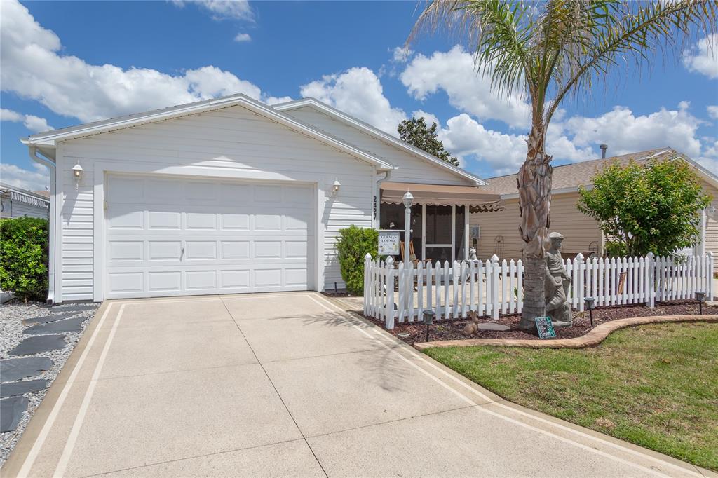 A white house with a garage, a concrete driveway, and a fenced front patio area — 2427 SOUTHERN OAK STREET, THE VILLAGES, FL