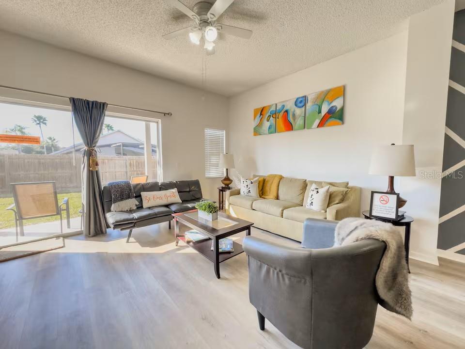 A living room features light wood-look flooring, a ceiling fan, and a sliding glass door — 910 PARK TERRACE CIRCLE, KISSIMMEE, FL