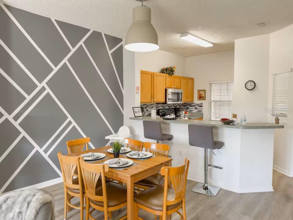 A dining area with a geometric accent wall and a kitchen with a breakfast bar — 910 PARK TERRACE CIRCLE, KISSIMMEE, FL