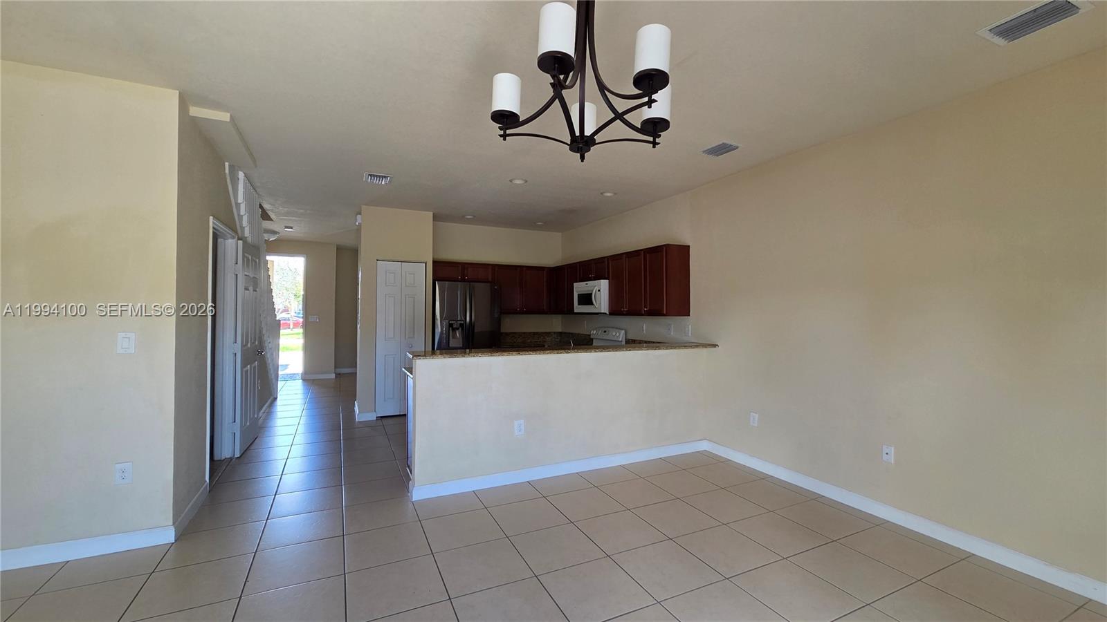 An open-concept kitchen with dark wood cabinets and a breakfast bar overlooks a tiled room — 9001 SW 227th St # 7, Cutler Bay FL 33190, CUTLER BAY, FL