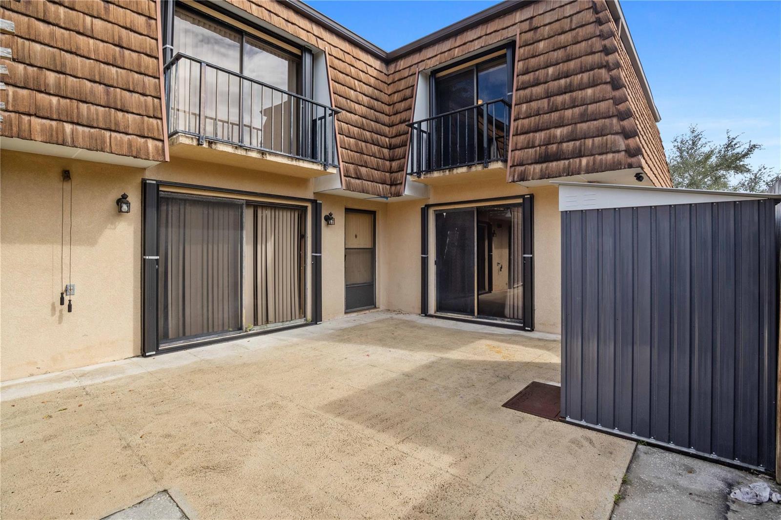 A concrete patio sits in front of a two-story building with brown shingled mansard siding — 1821 18th Lane, FL 33463, FL