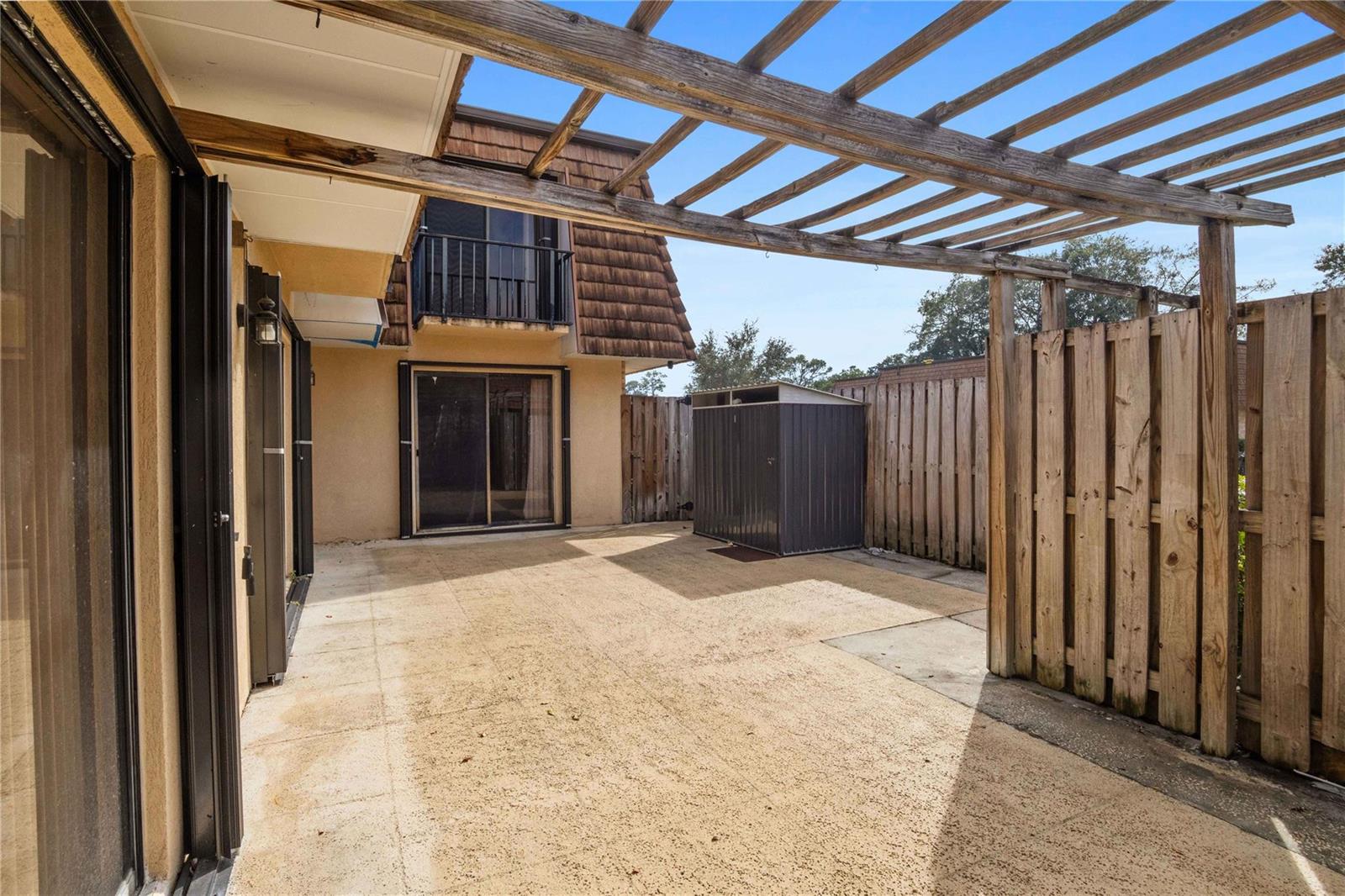 A concrete patio features a wooden pergola, a metal storage shed, and a wooden fence — 1821 18th Lane, FL 33463, FL