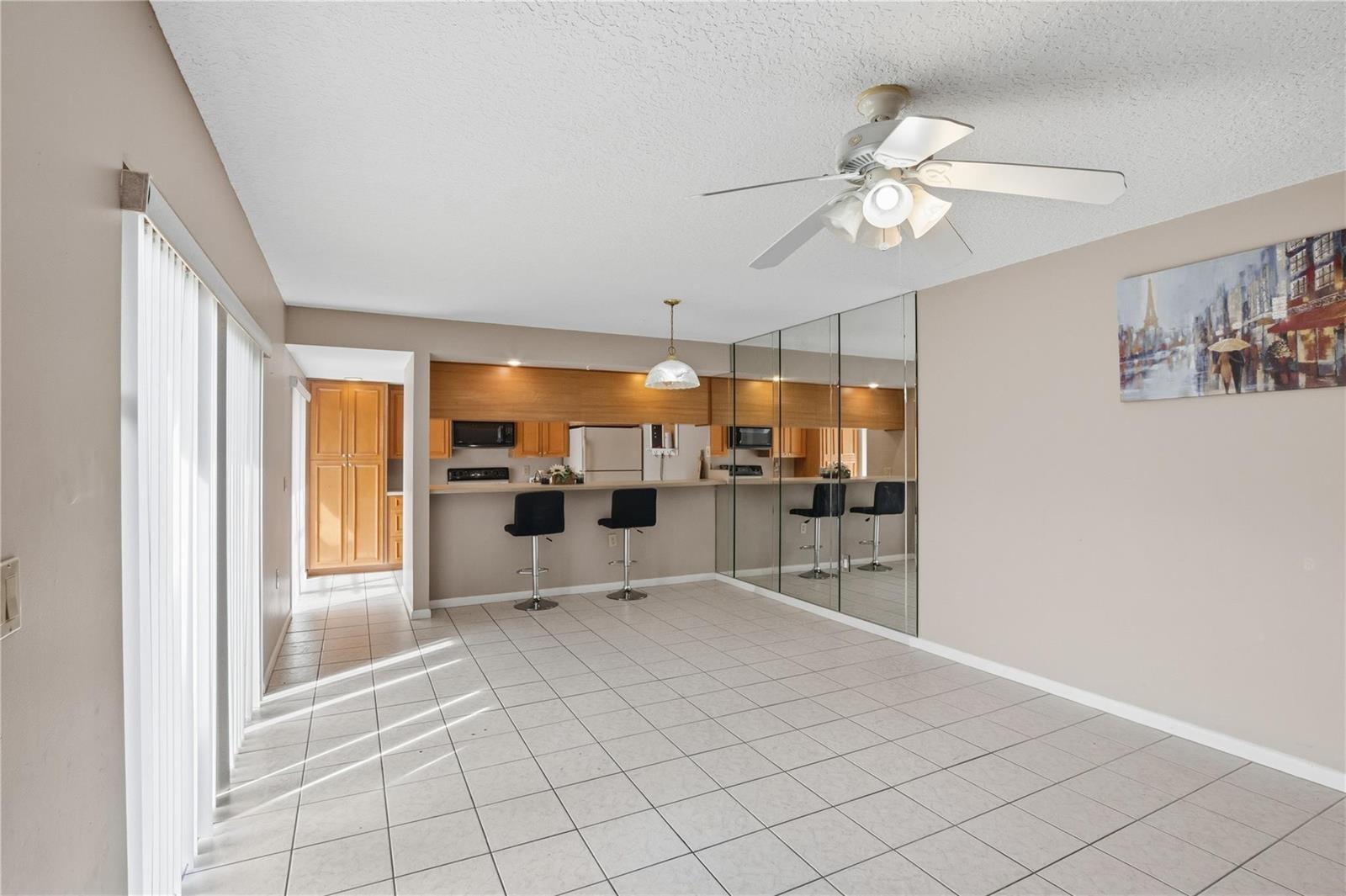 A dining area with tiled floors, a breakfast bar, mirrored walls, and a ceiling fan — 1821 18th Lane, FL 33463, FL