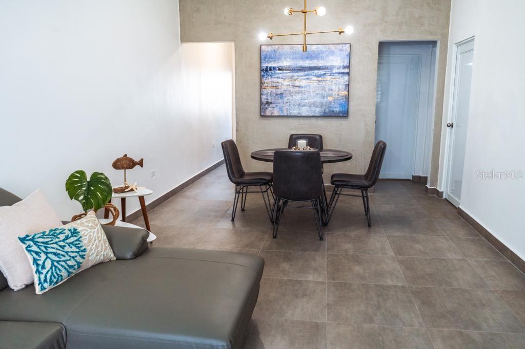 A dining area with a round table and chairs sits in front of a textured wall — 117 CALLE POMARROSA UNIT 3D, SAN JUAN, PR