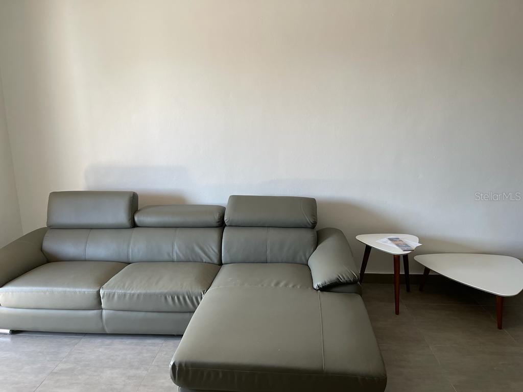 A gray leather sectional sofa sits on a tiled floor next to two small tables — 117 CALLE POMARROSA UNIT 3D, SAN JUAN, PR