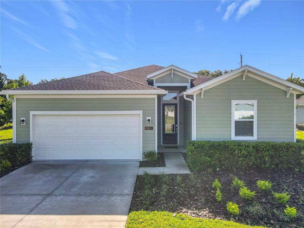 A single-story house with sage green siding, a white garage door, and a front entrance — 2183 RAGLAN CIRCLE, ORMOND BEACH, FL