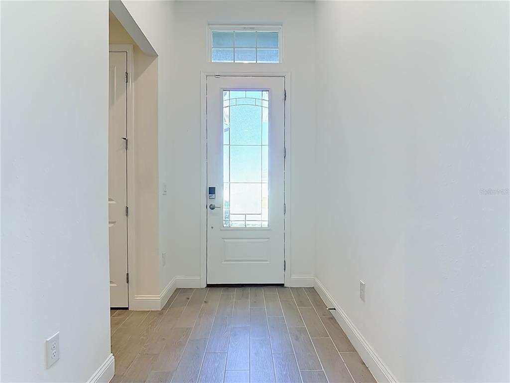 A bright entryway features a white front door with a transom window and wood-look flooring — 2183 RAGLAN CIRCLE, ORMOND BEACH, FL