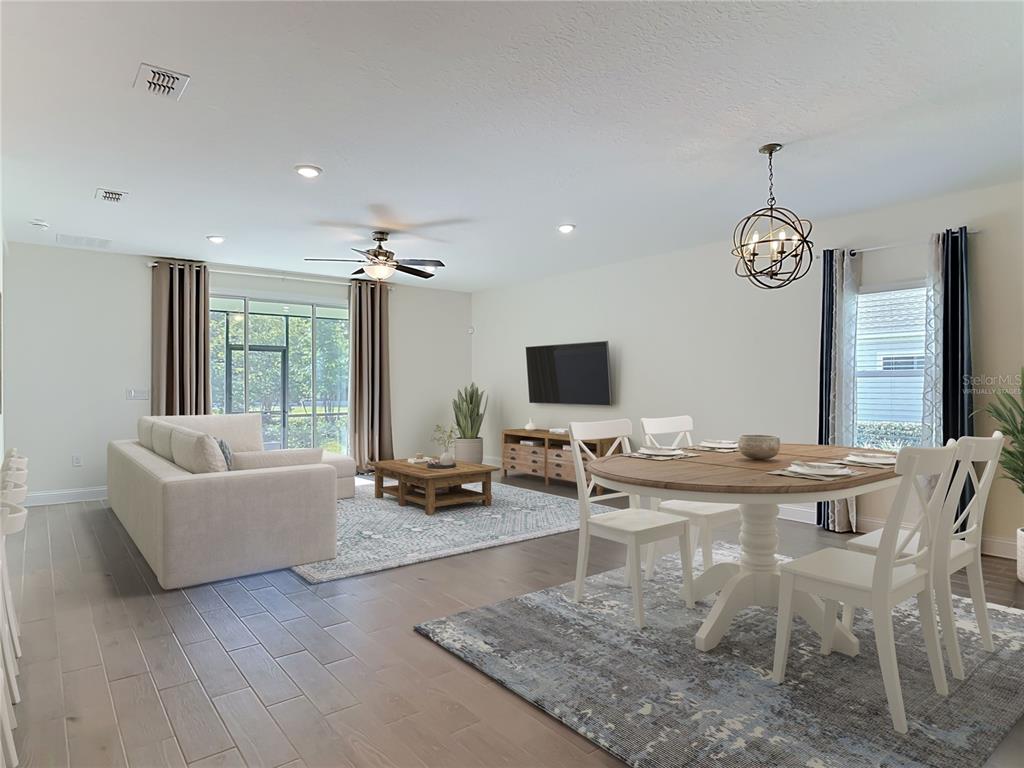 An open-concept living and dining area features light wood flooring, neutral walls, and large windows — 2183 RAGLAN CIRCLE, ORMOND BEACH, FL