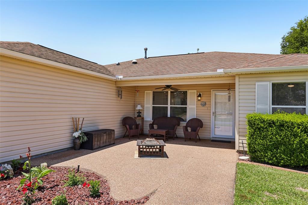 A beige-sided house features a covered patio with outdoor furniture and a fire pit — 1000 KENOVA AVENUE, THE VILLAGES, FL