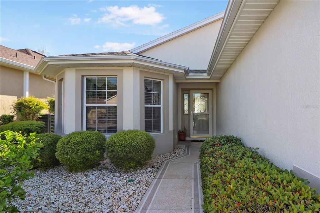 The exterior of a house features a concrete walkway leading to a front door entrance — 20846 QUEEN ALEXANDRA DRIVE, LEESBURG, FL