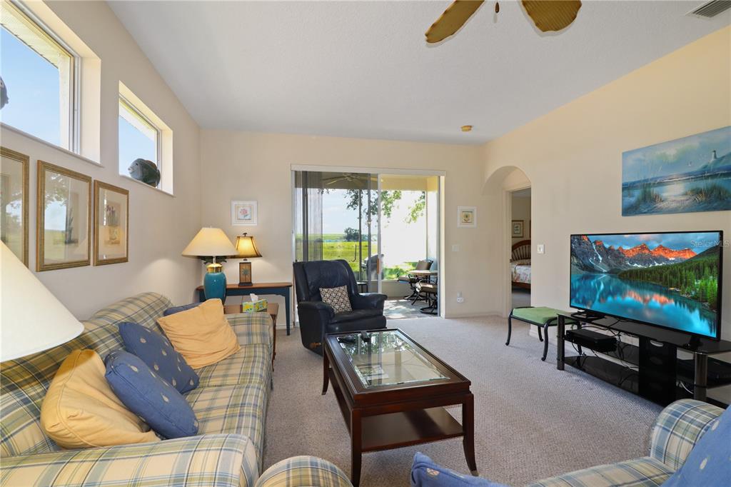 A living room with plaid furniture, a glass-top coffee table, and a sliding door to a patio — 20846 QUEEN ALEXANDRA DRIVE, LEESBURG, FL