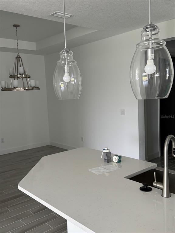 A kitchen island with a white countertop and pendant lights sits before a dining area — 10057 MORNING MIST LANE, SARASOTA, FL