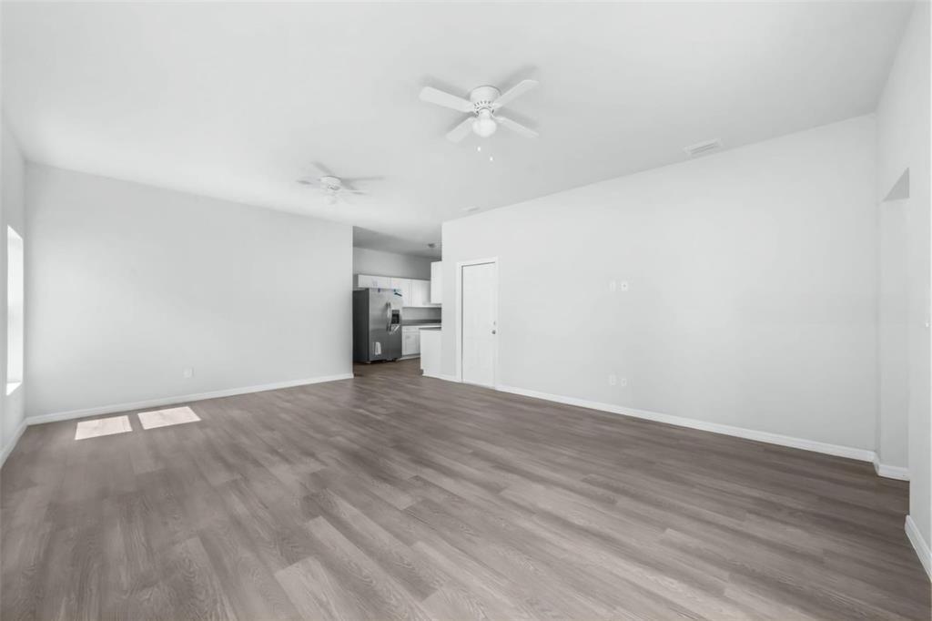 An open-concept living area features light gray walls, wood-look flooring, and two ceiling fans — 1450 Las Villas Boulevard, Sebring FL 33870, SEBRING, FL