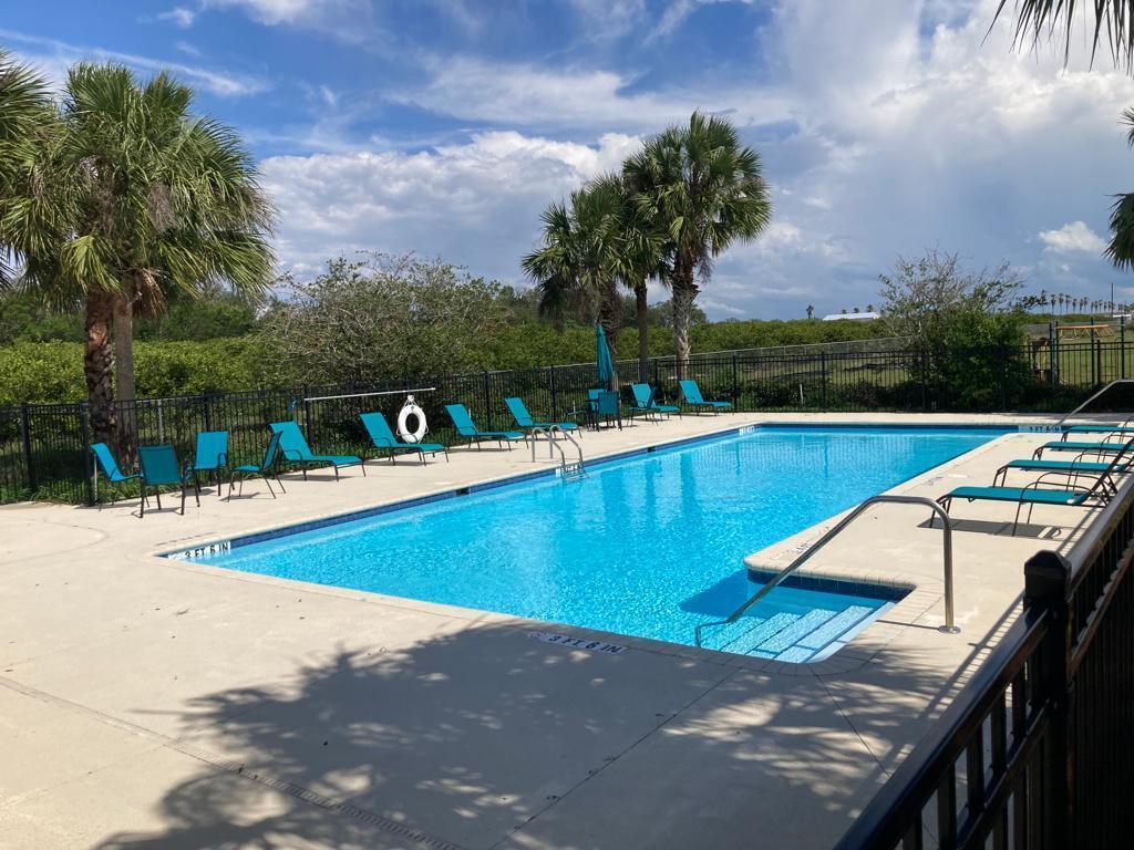 An outdoor swimming pool with lounge chairs and palm trees under a cloudy blue sky — 1450 Las Villas Boulevard, Sebring FL 33870, SEBRING, FL