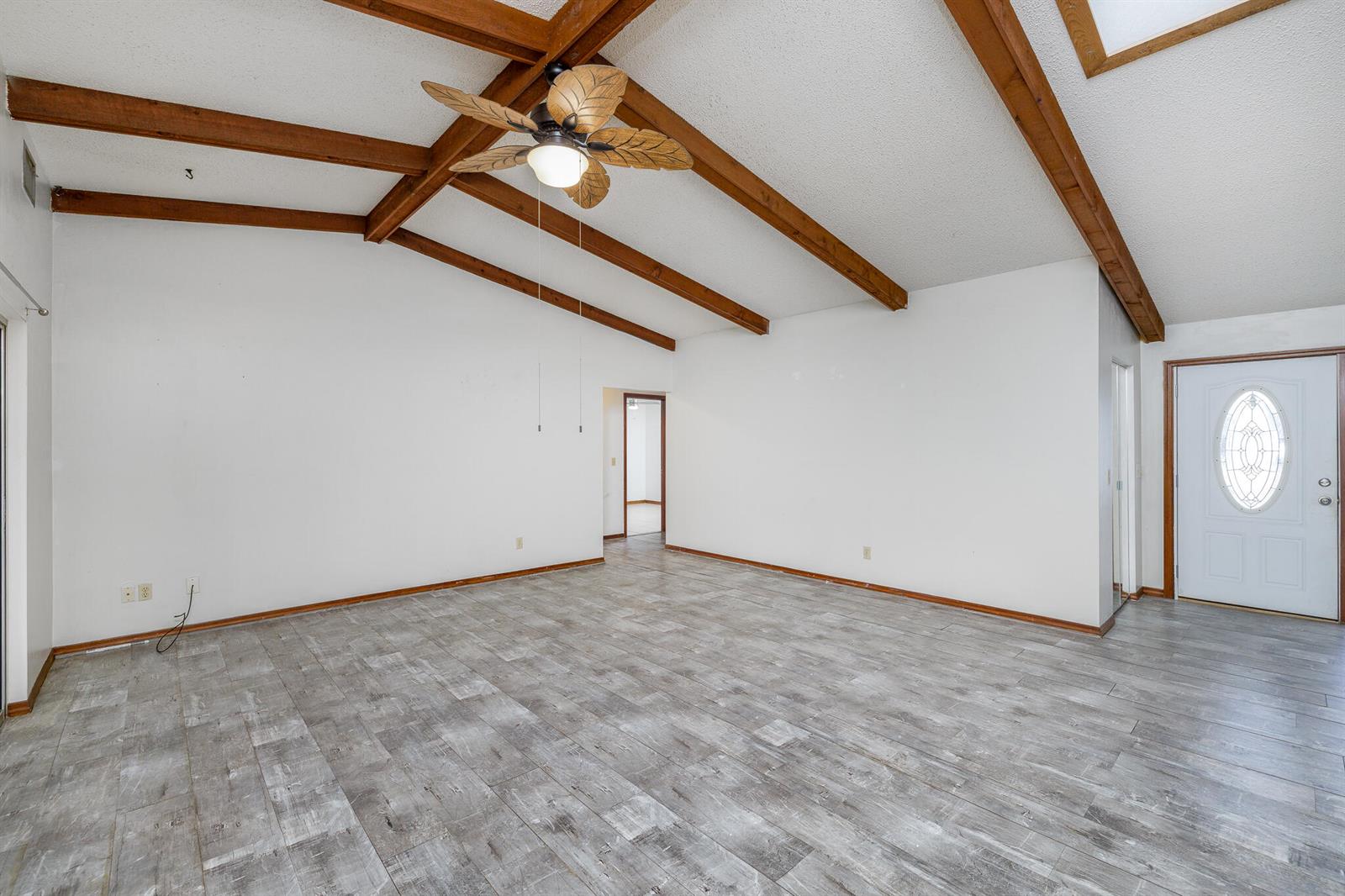 A living room with vaulted ceilings, exposed wood beams, a ceiling fan, and gray flooring — 4262 S Centennial Avenue, FL 34446, FL