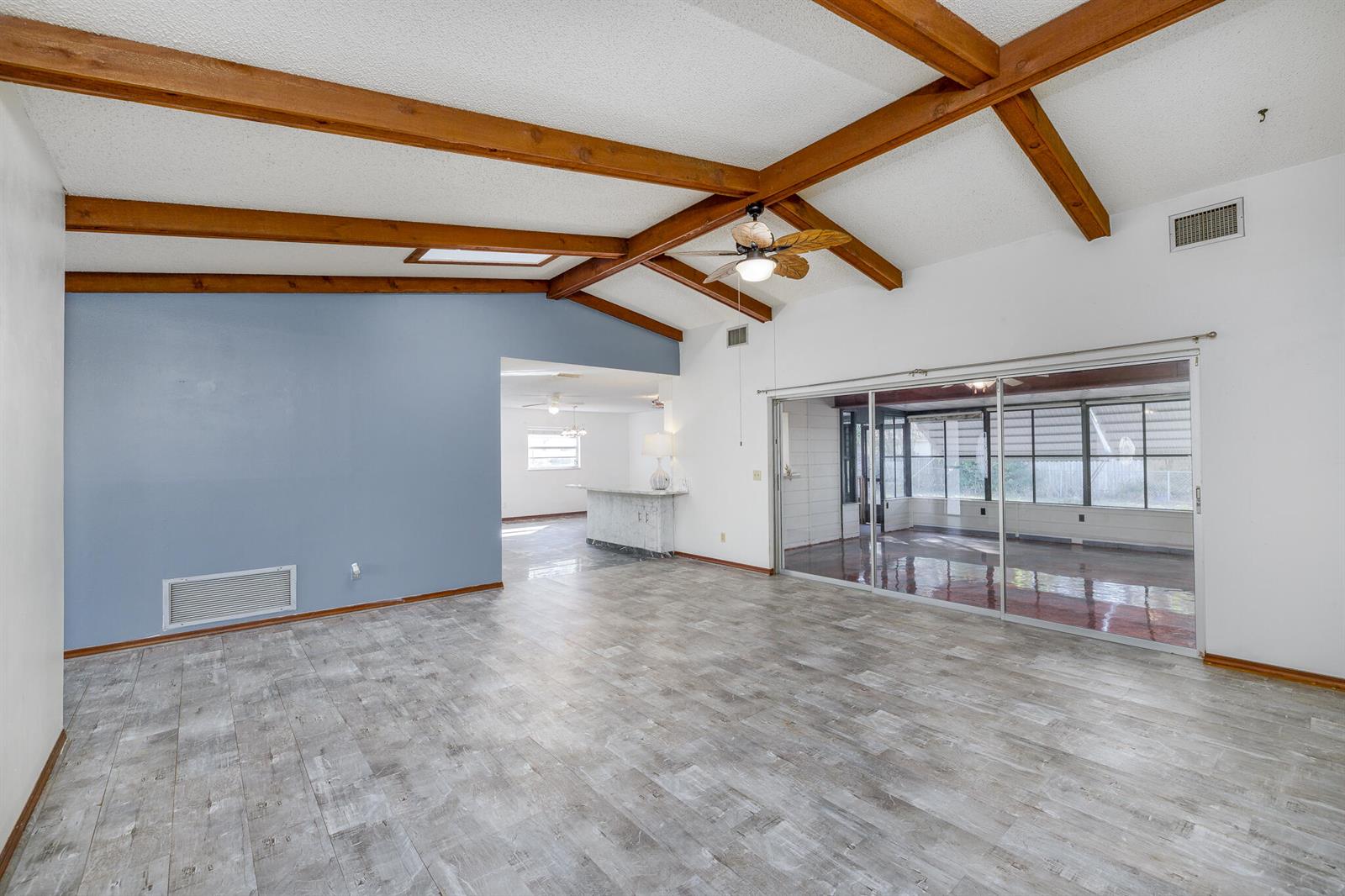 A living room features wood ceiling beams, gray wood-look flooring, and a sliding glass door — 4262 S Centennial Avenue, FL 34446, FL